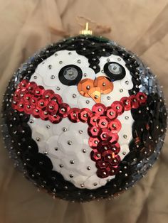 a christmas ornament with a snowman face on it's side and red, white, and black sequins