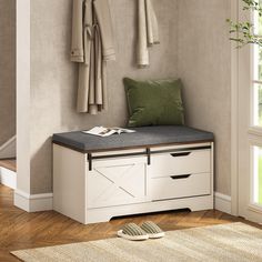 a white bench sitting next to a window with green pillows and blankets on top of it