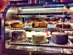 a display case filled with lots of different types of cakes and pies in it