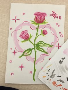 a drawing of a pink rose with butterflies on it next to a piece of paper