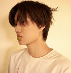 a young man with a flower in his mouth looking off to the side while wearing a white t - shirt