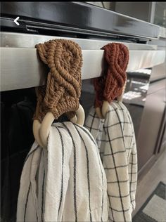 two knitted hats hanging from the handle of an oven