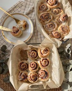 two trays filled with cinnamon rolls on top of a table next to a plate