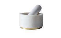 a white marble mortar and pestle with gold rim