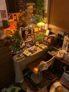 a room with many plants and pictures on the wall, including an office desk in front of a window