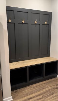 an empty room with several black lockers on the wall and wood flooring in front of it