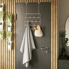 a bathroom door with towels hanging on the hooks and potted plants in pots next to it