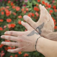 two hands that have tattoos on them and one is holding the other's hand