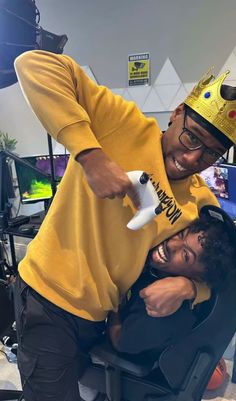 a man in a yellow shirt with a crown on top of his head and another person holding a video game controller