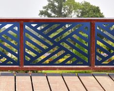 a wooden deck with blue metal railing and trees in the background