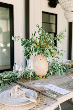 the table is set with an olive tree centerpiece and place settings for two people