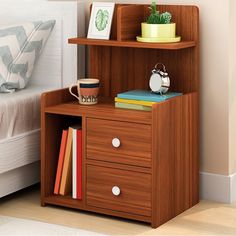 a small wooden shelf with two drawers next to a bed and nightstand in a bedroom