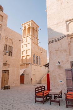 two wooden benches sitting next to each other in front of a tall building with a clock tower