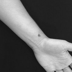 a person's left hand with a small tattoo on the middle of their wrist