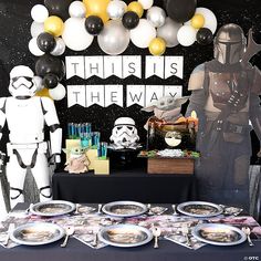 a star wars themed party with balloons, plates and desserts on the buffet table