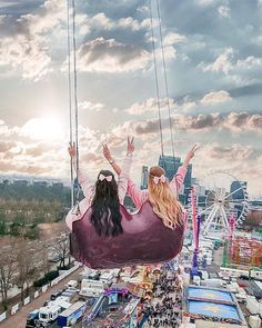 a woman sitting in a hammock suspended over a fairground with her hands up