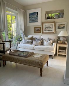 a living room filled with furniture and pictures hanging on the wall above it's windows