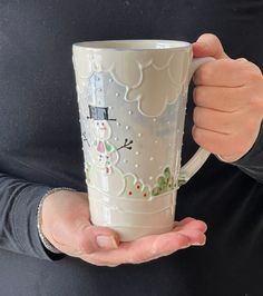 a person holding a frosty cup in their hands with snowmen on the side