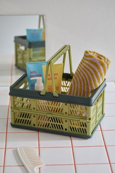 a yellow basket filled with items on top of a white tiled floor next to a comb