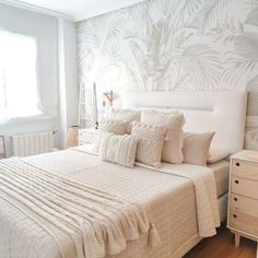 a bed with white sheets and pillows in a bedroom