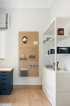 a room with white walls and wooden flooring next to a shelf filled with items