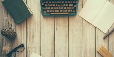 an old fashioned typewriter sitting on top of a wooden table next to other items