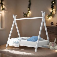 a child's bed with a white wooden frame and blue blanket on the bottom