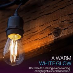 a light bulb that is on the side of a wooden wall with an advertisement for a warm white glow