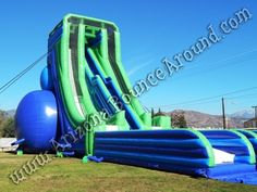 an inflatable water slide with blue and green balls on the ground next to it