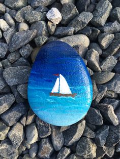 a painted rock with a sailboat on it