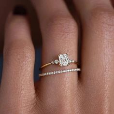 a woman's hand with a diamond ring on her finger and the other hand holding an engagement ring