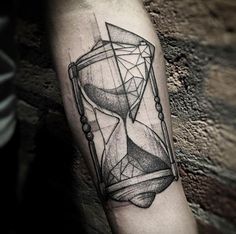 a man's arm with an hourglass tattoo on it, which is black and white