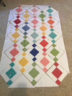 the quilt is laying on the floor with it's squares laid out in rows