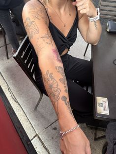 a woman sitting at a table with tattoos on her arms and arm, holding an umbrella