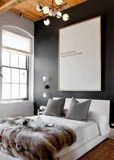 a bedroom with black walls, white bedding and fur rugs on the floor