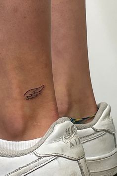 a woman's foot with a small wing tattoo on her left side calfocks