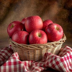 a basket filled with red apples sitting on top of a table