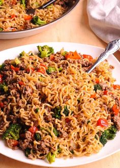 two plates filled with noodles, meat and vegetables