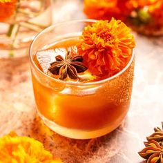 an orange flower in a glass with ice and cinnamon on the table next to it