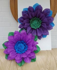 two purple and blue flowers sitting on top of a couch