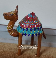 a wooden toy camel with a colorful hat on its head sitting on the floor next to a wall