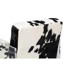 a cow print chair and foot rest on a white background, with the seat upholstered in black and white