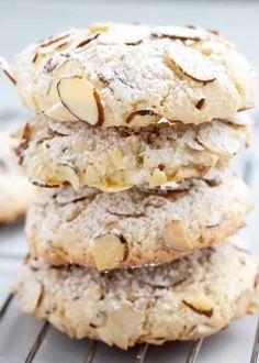 a stack of cookies with almonds and powdered sugar on top, sitting on a cooling rack