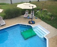 an empty swimming pool with lawn chairs and umbrellas next to the water's edge