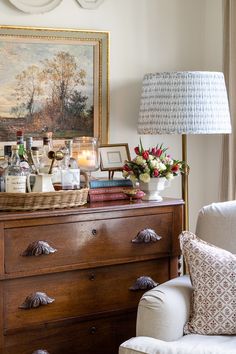 a living room with an old dresser and painting on the wall above it, filled with liquor bottles