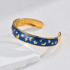 Elevate your style with this beautifully crafted 18K gold-plated bangle, featuring a rich dark blue enamel and sparkling rhinestone stars and moons. Made from durable 304 stainless steel, its retro-inspired design captures the allure of the night sky. With a 6.1cm diameter, this bracelet is perfect for adding a touch of celestial charm to any outfit, whether for a special occasion or everyday elegance. Celestial Gold Bracelet, Celestial Blue Jewelry With Moon Charm, Blue Star-shaped Celestial Jewelry, Celestial Gold Star Bracelets, Celestial Bracelet With Star Charm, Celestial Bracelet, Celtic Moon, Stars And Moons, Everyday Elegance