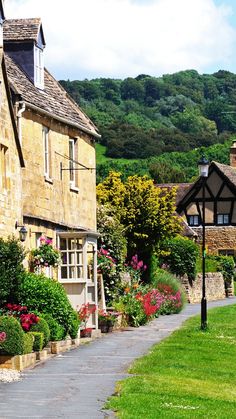 an old stone building with flowers in the foreground and a pathway leading to it