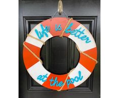 a red and white life preserver hanging on a door with the words we is better at the pool