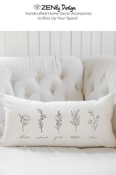 a white couch with a pillow on top of it and three different plants drawn on the back