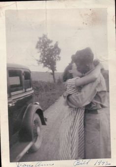 an old black and white photo of two people hugging on the side of a road